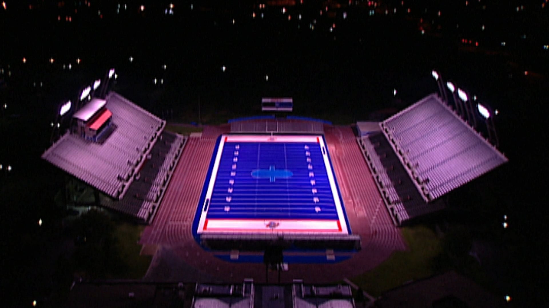 video still of a blue football field with stadium seating at night