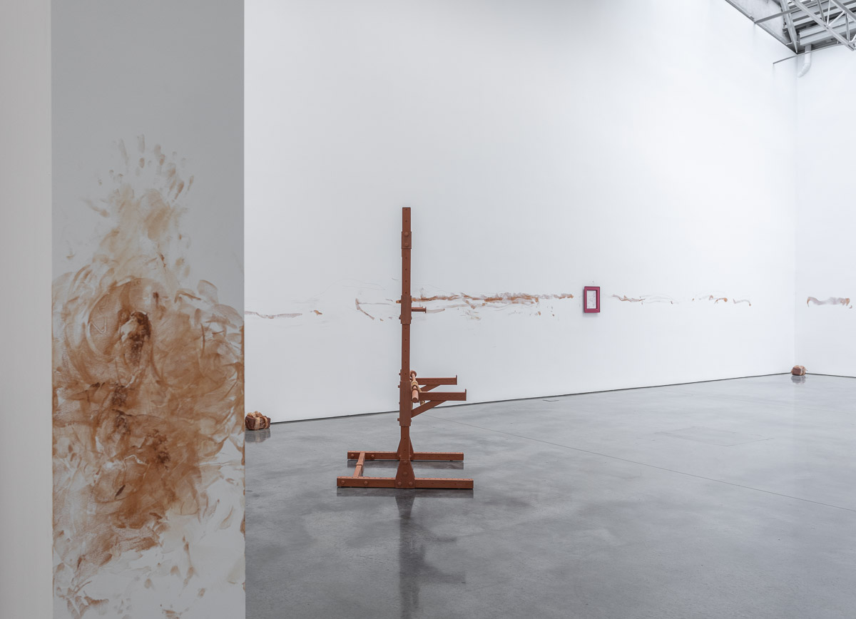 Art exhibition installation with pigment and framed art on the walls of the room and sculptures on the floor. 