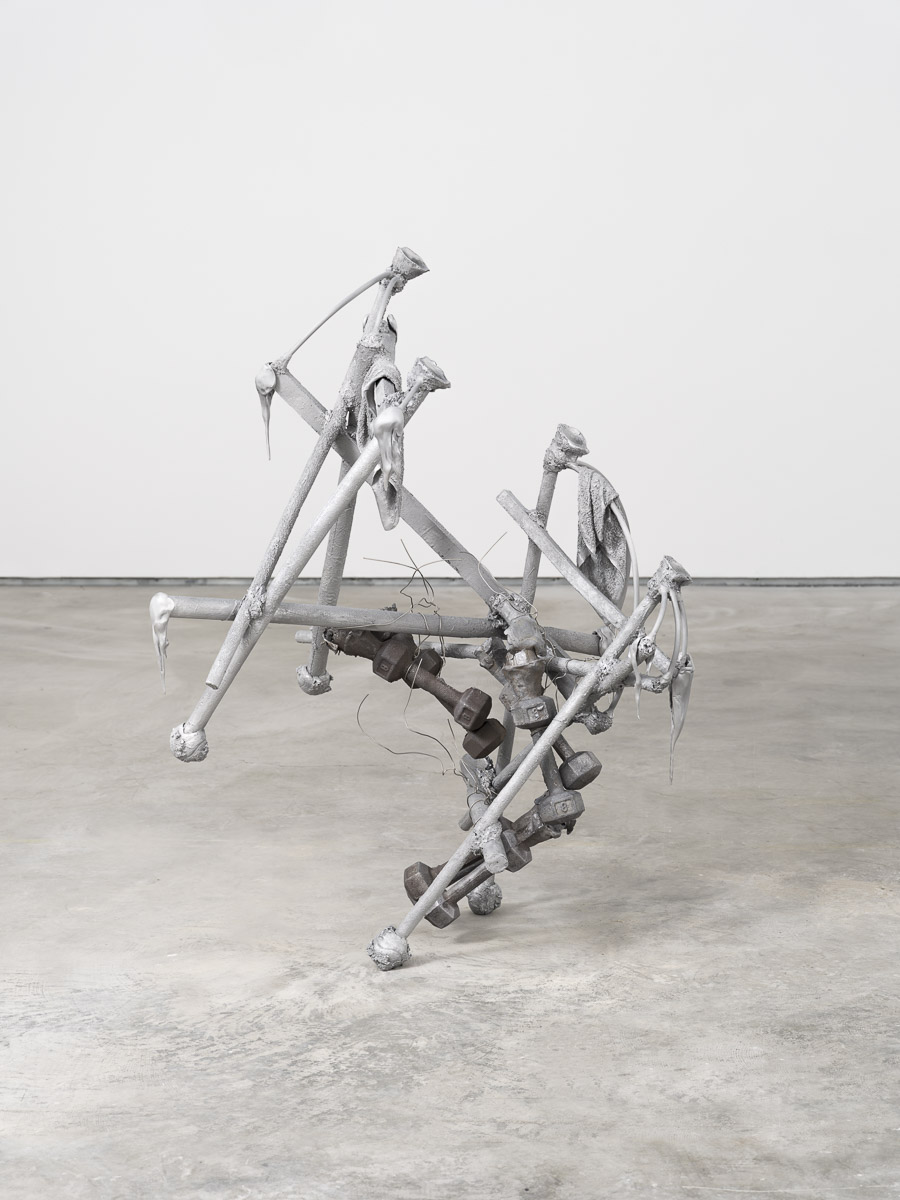 Aluminum and lead sculpture in a white room with concrete floor.