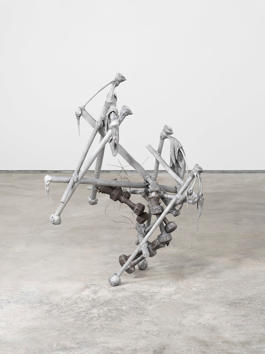 Aluminum and lead sculpture in a white room with concrete floor.