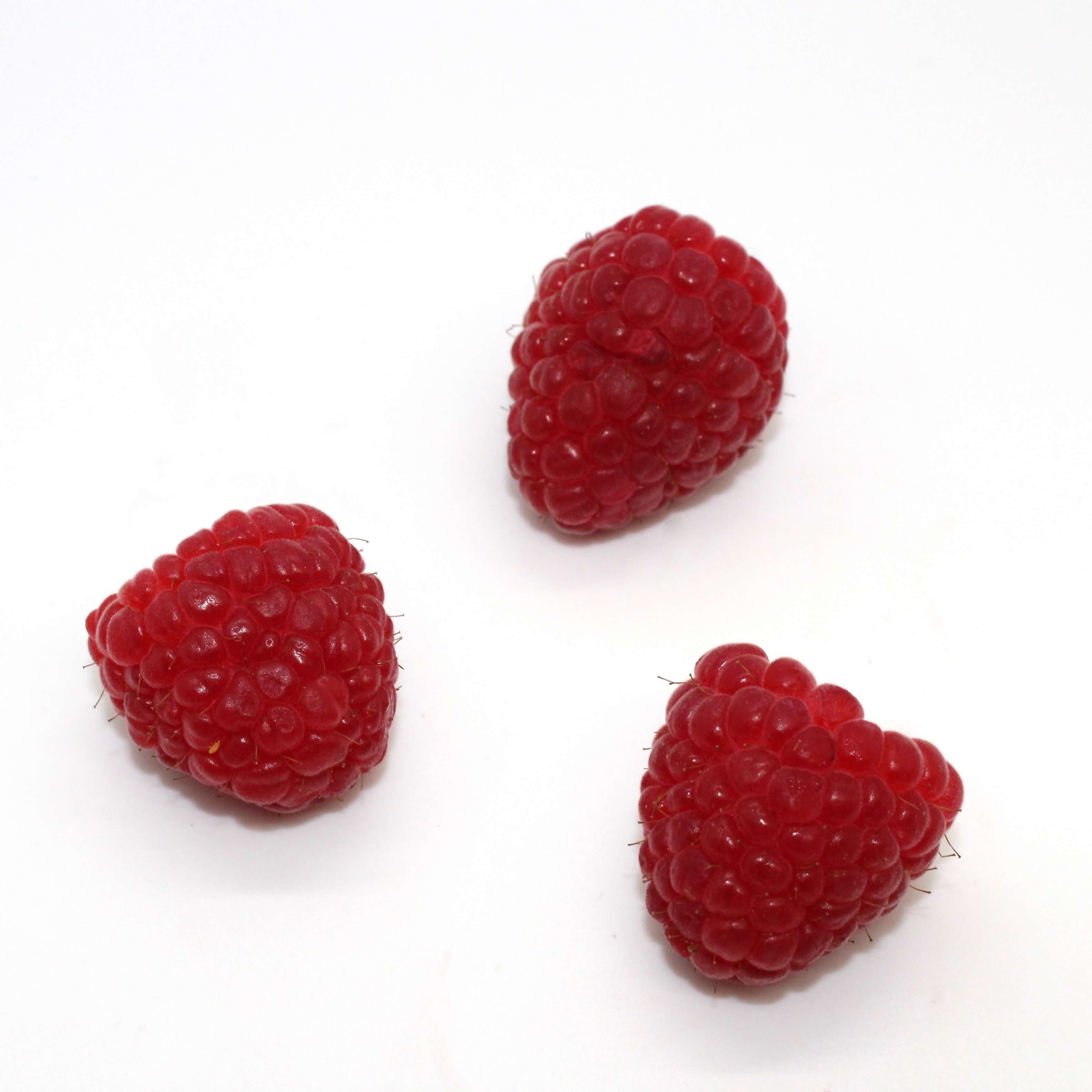 3 raspberries on a white background