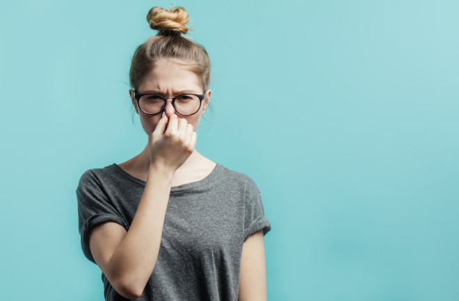 woman wearing glasses holding her nose from a smelly fart