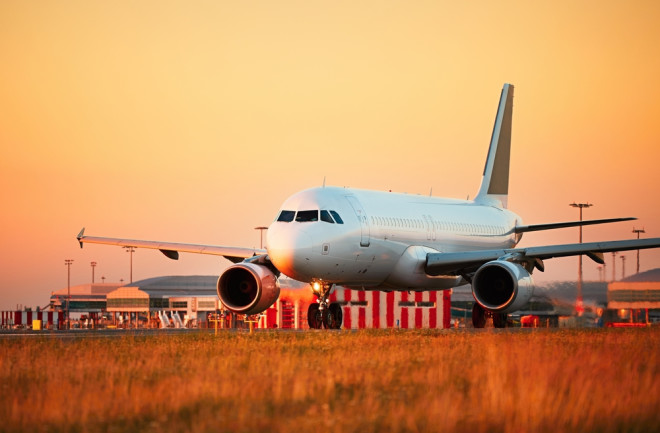 airplane is grounded against a sunset orange yellow sky - shutterstock