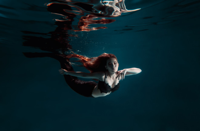 Underwater swimming mermaid freediver girl with tale and red hair