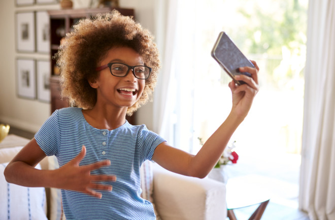 Young Girl Child Using Smartphone Social Media Technology - shutterstock 1300416679