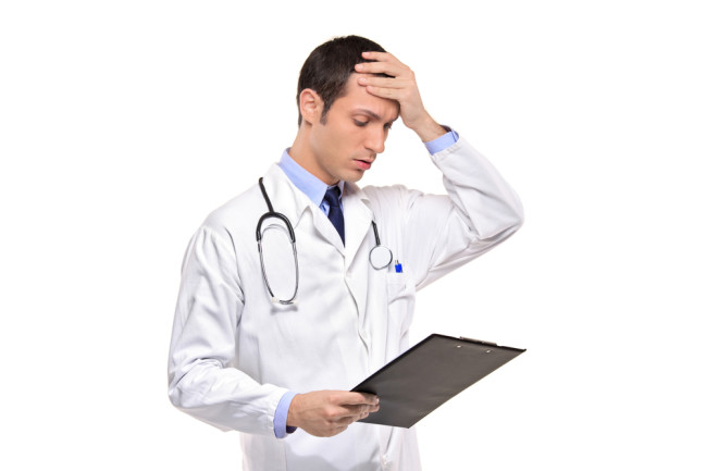 doctor looking distressed at clipboard after a surgical mistake