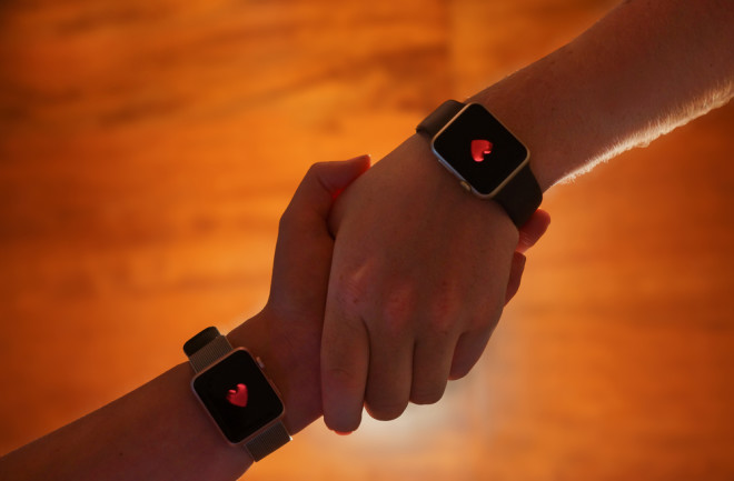 holding hands wearable device showing a heart icon - shutterstock 692318383