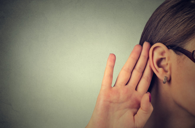 Woman with hand up to her ear, listening hearing - Shutterstock