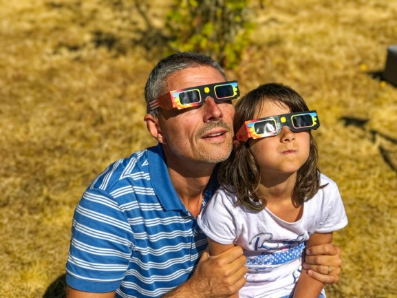 father and daughter watching eclipse with eclipse glasses