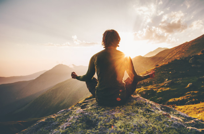 person is meditating on a mountain - shutterstock 617840372