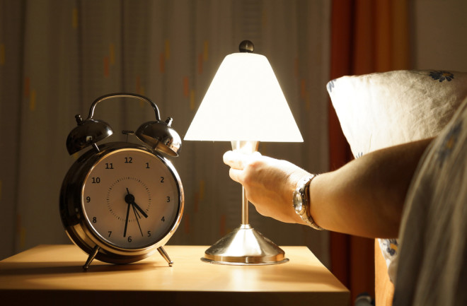Arm reaches out of bed and turns on a light in the middle of the night - Shutterstock