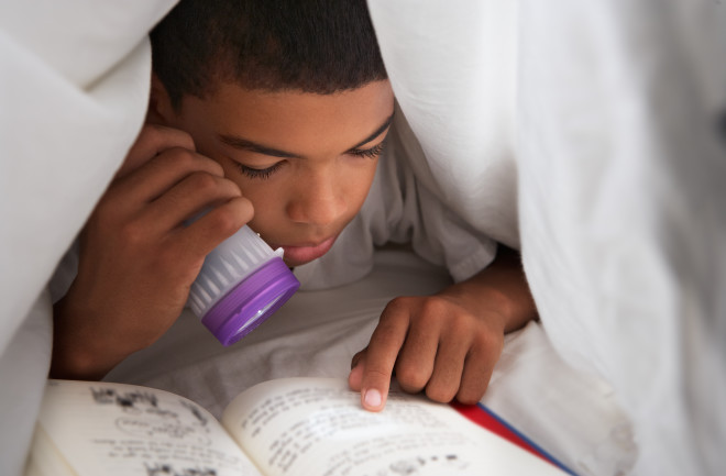 Boy Child Reading in Bed Flashlight - Shutterstock