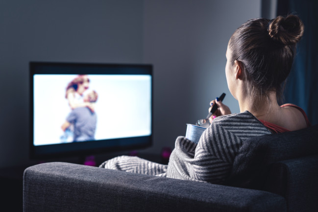 Woman watching romantic movie and eating ice cream