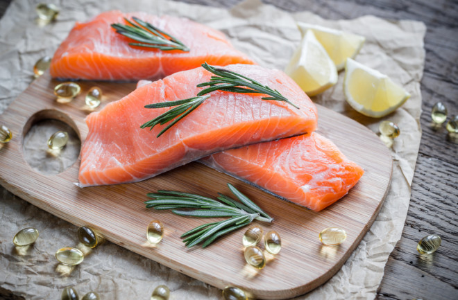 salmon and omega 3 capsules on a cutting board with lemon heart healthy diet - shutterstock