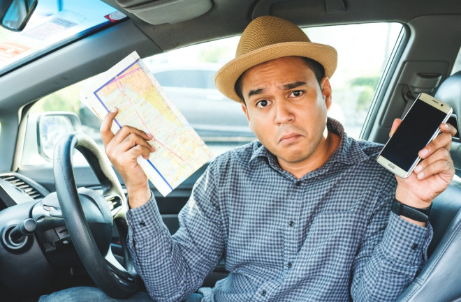 a man holding a map and a smartphone - getting lost navigation - shutterstock 643618435