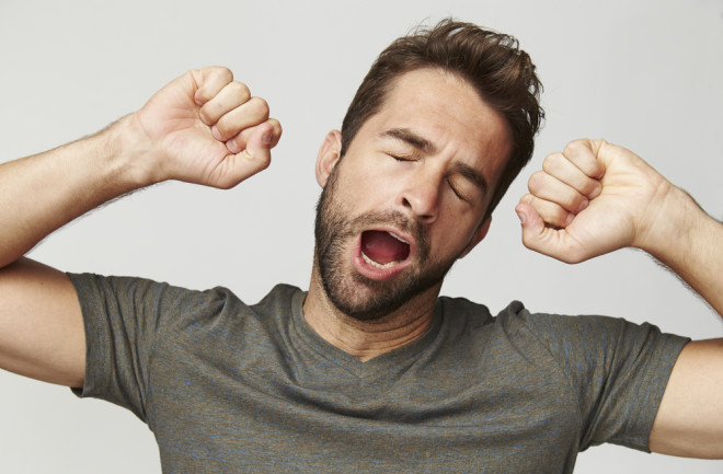 Man streching arms out while yawning with eyes cold