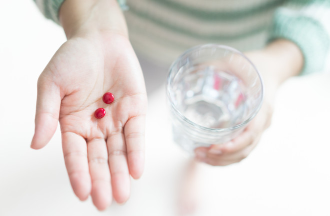 Close Up Of Girl holding Red Pill and glass of water.With Iron of tummy or pregnant. Nutritional Supplements.Sport,pregnancy Concept.Capsules Vitamin And Dietary Supplements.