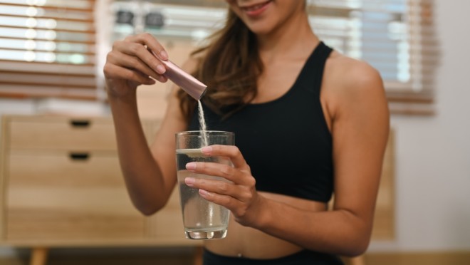 woman putting collagen powder in water