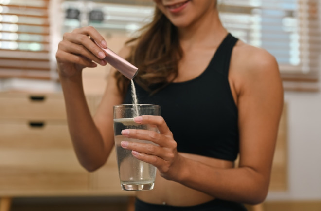 woman putting collagen powder in water