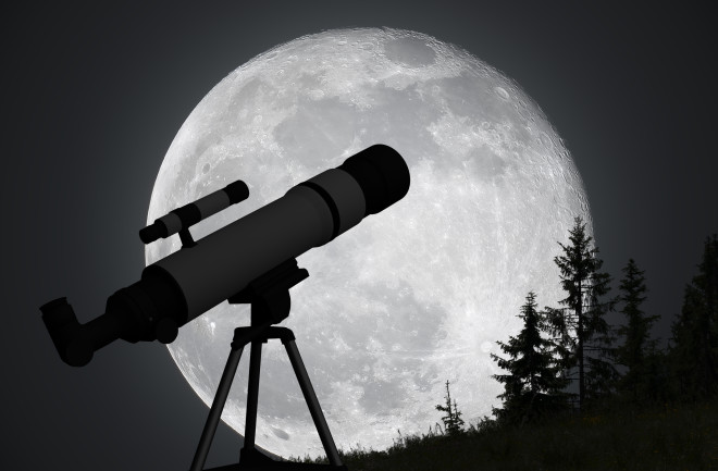 Silhouette of telescope and big moon in background.