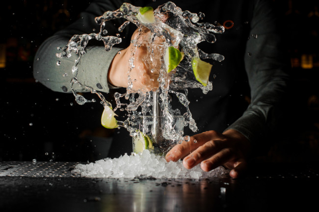 Hands violently stirring a cocktail and spilling - Shutterstock