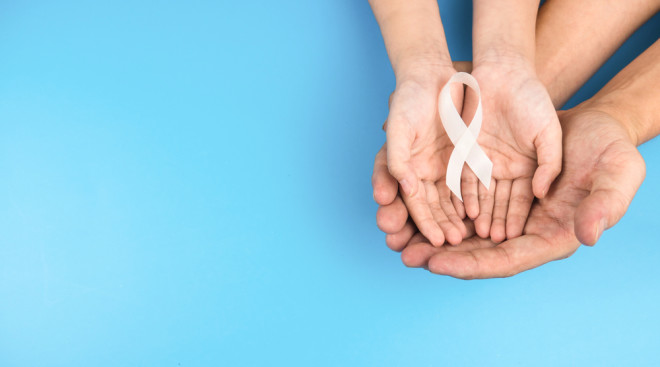 hands holding a white ribbon cancer awareness - shutterstock 1726701073