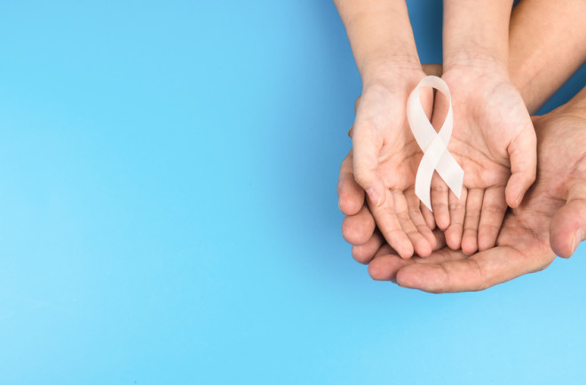 hands holding a white ribbon cancer awareness - shutterstock 1726701073