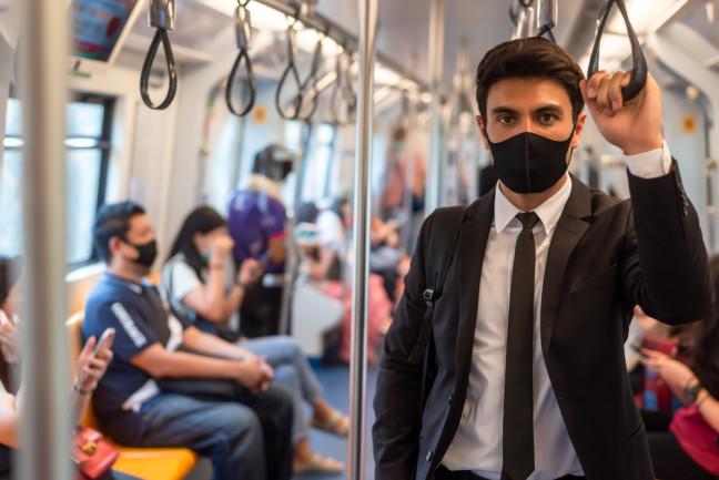 pandemic coronavirus masked man on a bus - shutterstock