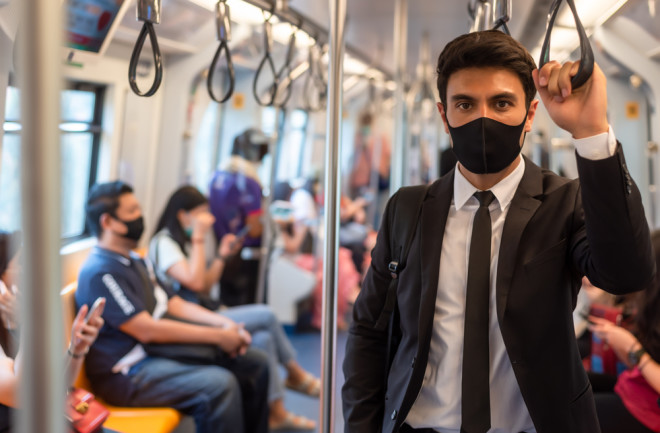 pandemic coronavirus masked man on a bus - shutterstock