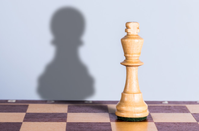queen chess piece with pawn shadow