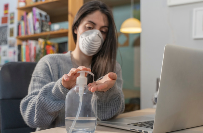 woman mask sanitizer computer work from home - shutterstock