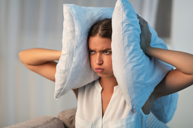 woman covering ears with pillow