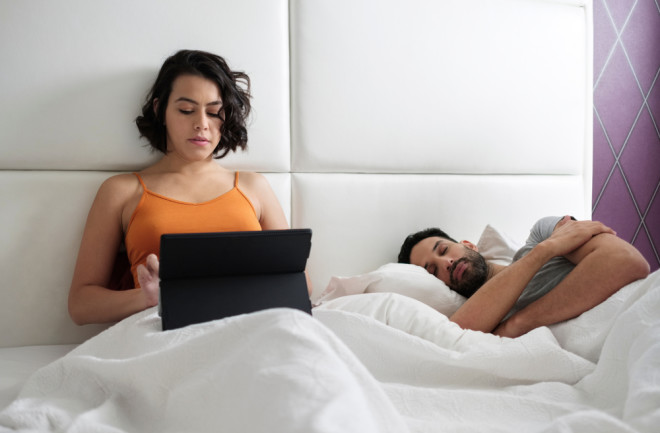 awake asleep couple bed laptop - Shutterstock