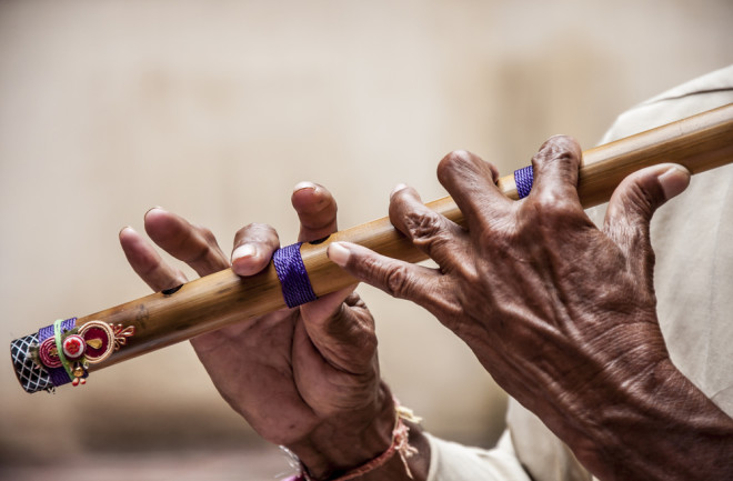 Hands playing a wooden flute - shutterstock