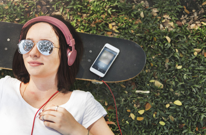 teenager listening to music on skateboard - shutterstock