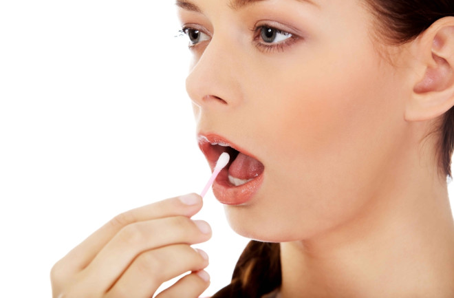 young woman swabbing mouth dna - shutterstock