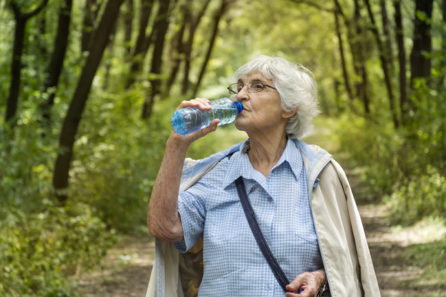elderly person drinking water in nature
