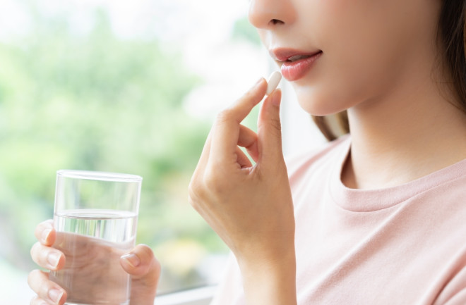 woman-holding-water-taking-a-supplement