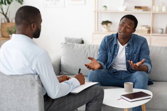Stressed man explaining his problems to psychologist at individual therapy session at office