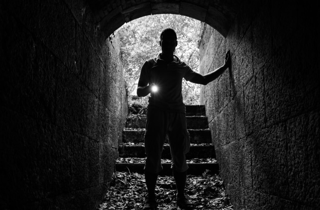 man in tunnel with flashlight