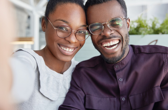 Smiling man and woman, both wearing glasses - Shutterstock