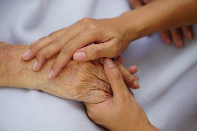 Caregiver holding hands with someone during end of life care
