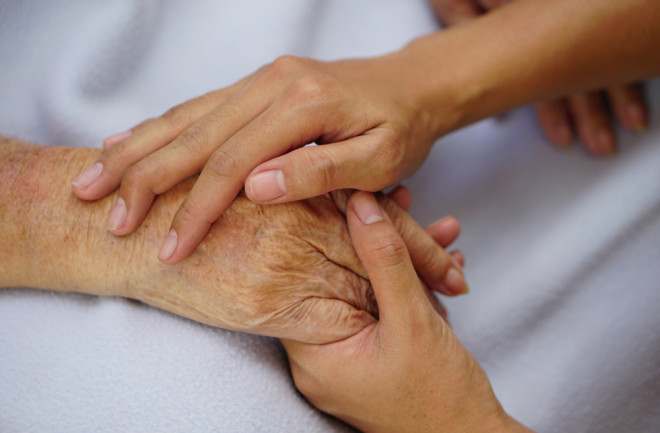 Caregiver holding hands with someone during end of life care