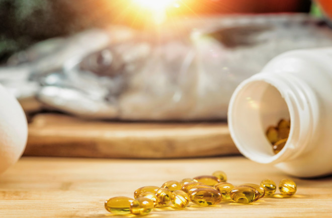 vitamin D Supplement Bottle with Gel Capsules On a Wooden Table. Natural Food Sources of Vitamin D In Background.