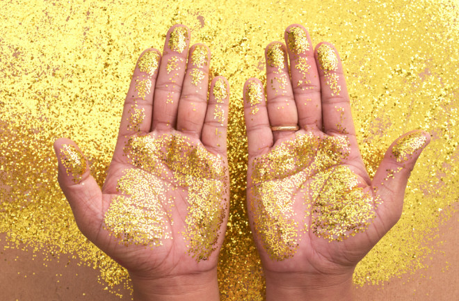 Hands hovering above a table with bright gold glitter