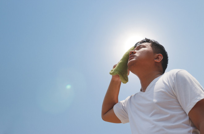 Young man standing outside in the sun with heat stroke