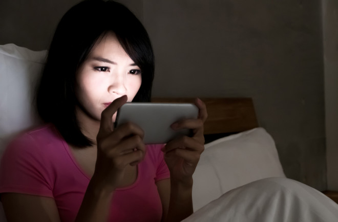 Woman on Phone in Bed Social Media Facebook - Shutterstock