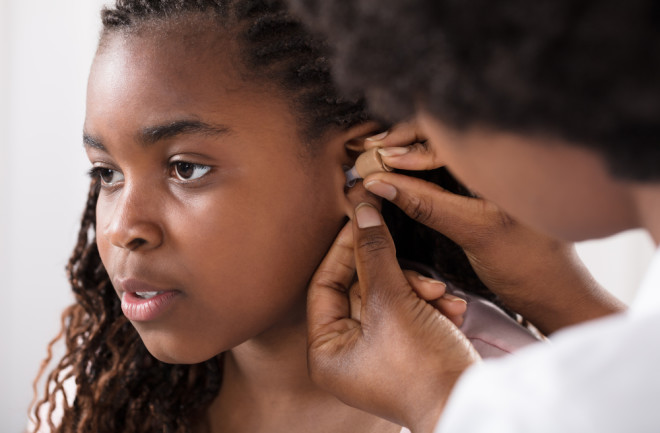 Young Girl Receives Hearing Aid from Doctor - Shutterstock