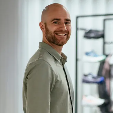A man with his hands in his pockets smiling at the camera.