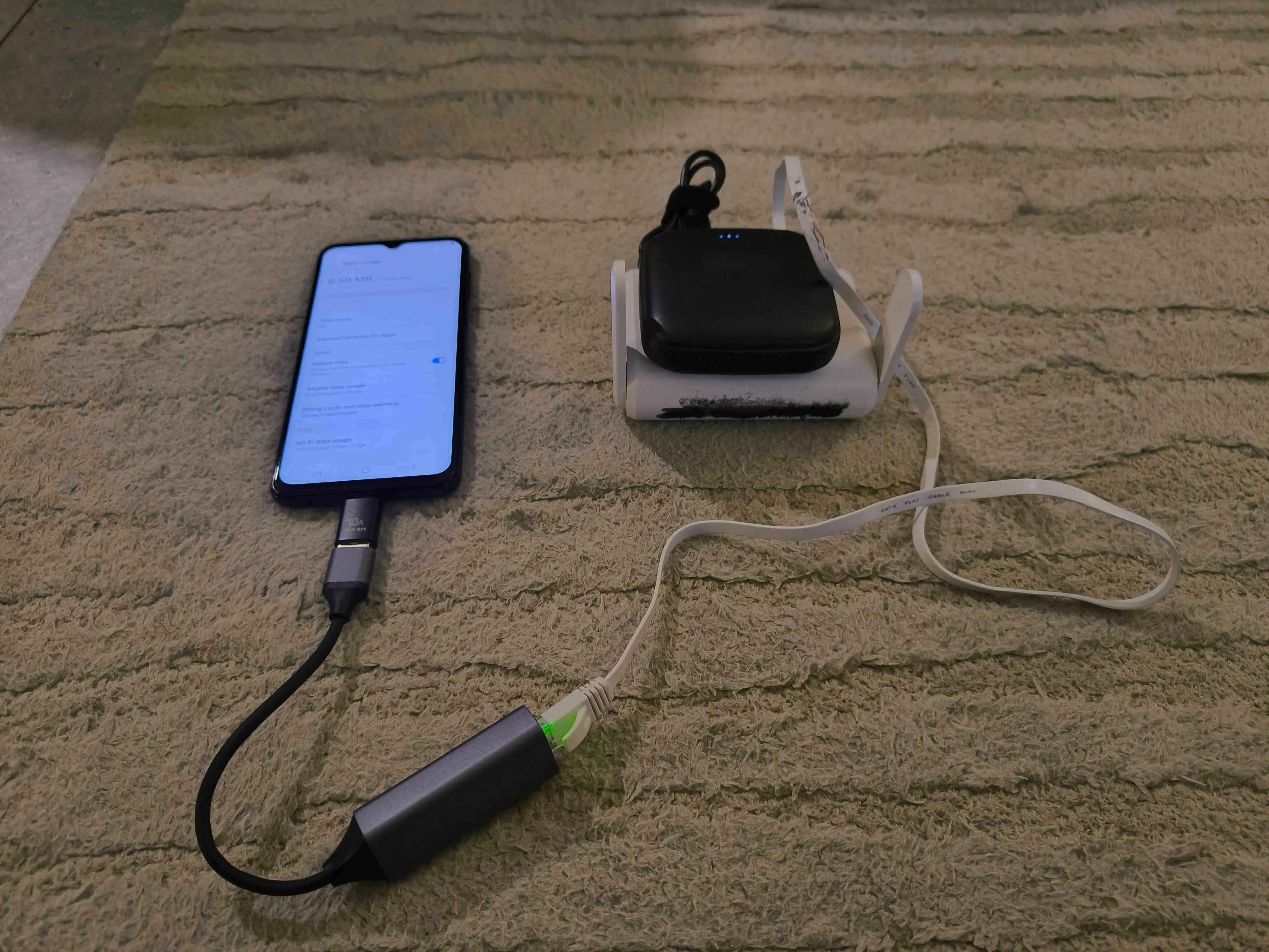 Photo showing the full setup: Android phone with USB-C ethernet adapter connected to GL.iNet travel router on power bank